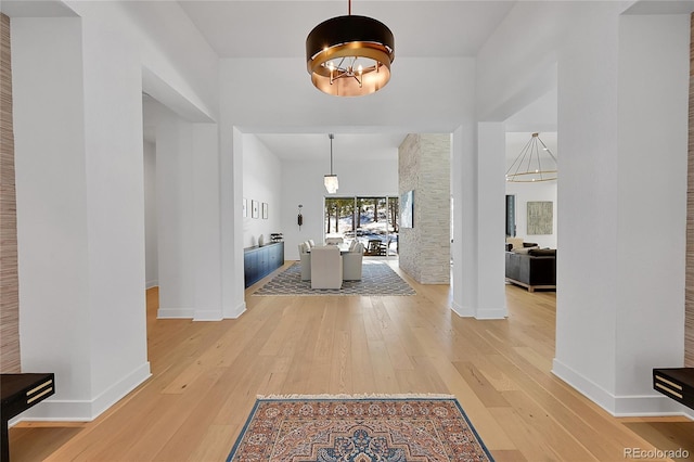 entrance foyer with light wood-style flooring, baseboards, and a chandelier