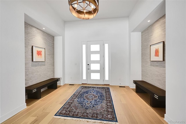 foyer entrance with a chandelier, wood finished floors, baseboards, and an accent wall