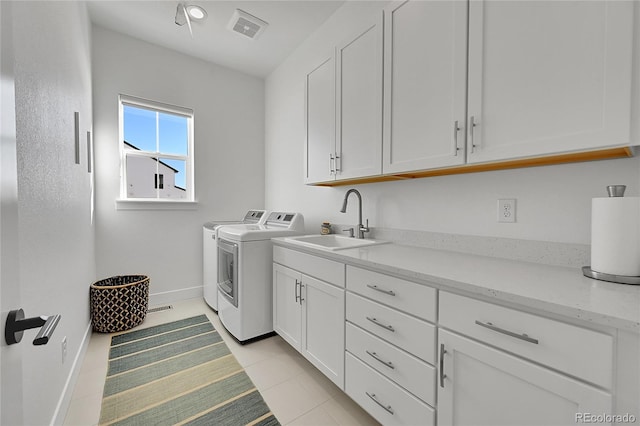 laundry room featuring washing machine and clothes dryer, cabinet space, baseboards, and light tile patterned floors