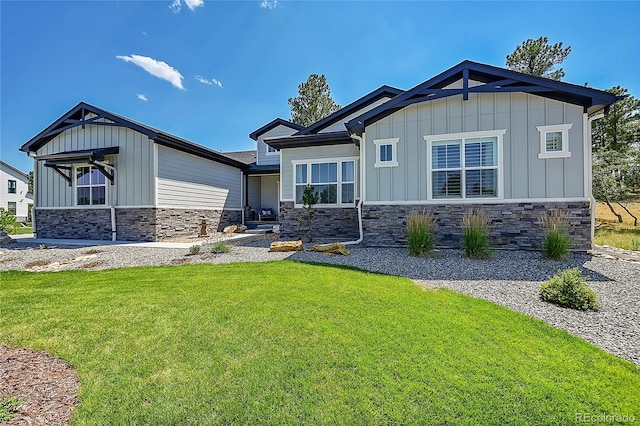 rear view of house with stone siding, board and batten siding, and a yard