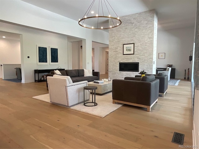 9228 Lone Timber Ct, Parker, CO 80134 - living room with light wood finished floors, a stone fireplace, and a chandelier