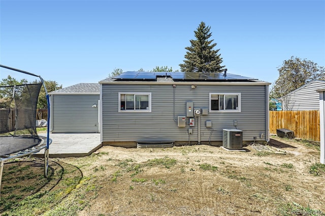 1958 Cathay Ct, Aurora, CO 80011 - back of house with a trampoline, central AC unit, a fenced backyard, and roof mounted solar panels