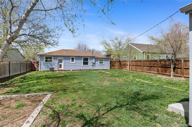 rear view of house with a lawn and a fenced backyard