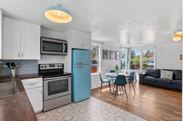 kitchen featuring white cabinets, stainless steel appliances, decorative backsplash, and ceiling fan