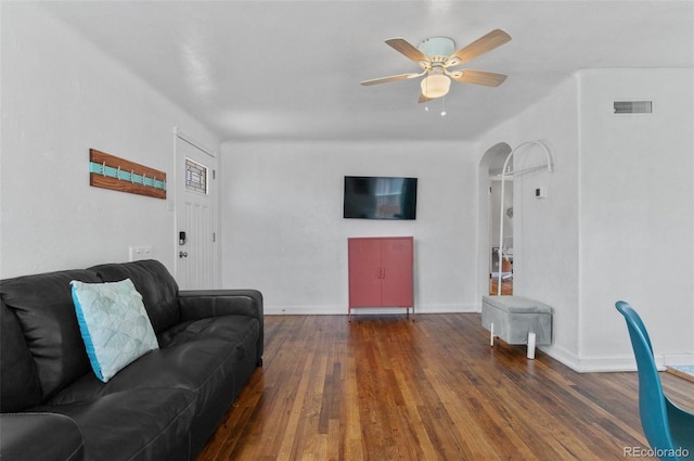living room featuring wood finished floors, visible vents, a ceiling fan, arched walkways, and baseboards