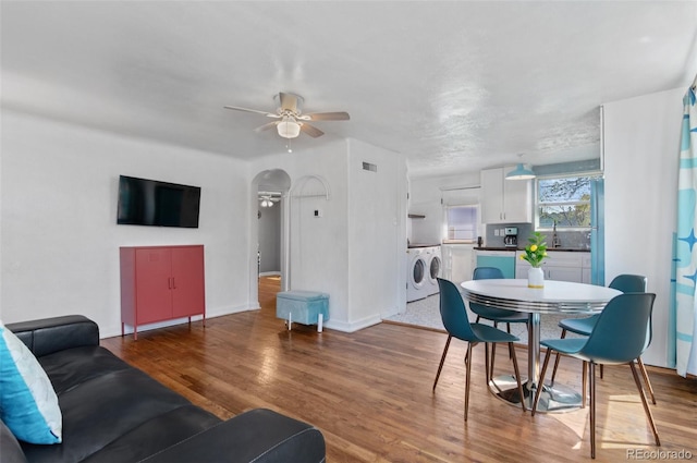 living room with wood finished floors, ceiling fan, arched walkways, baseboards, and visible vents