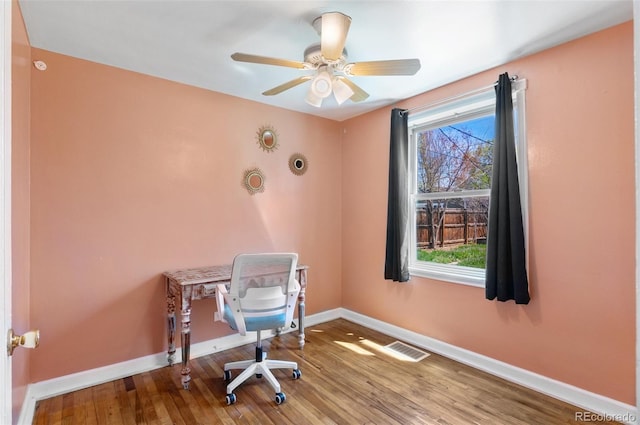 unfurnished office with baseboards, wood finished floors, visible vents, and a ceiling fan