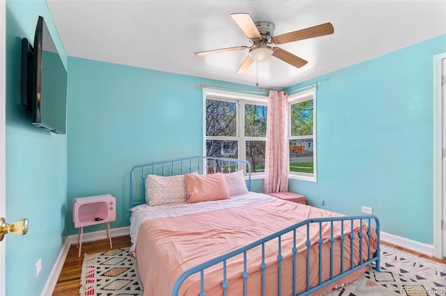 bedroom featuring ceiling fan, baseboards, heating unit, and wood finished floors
