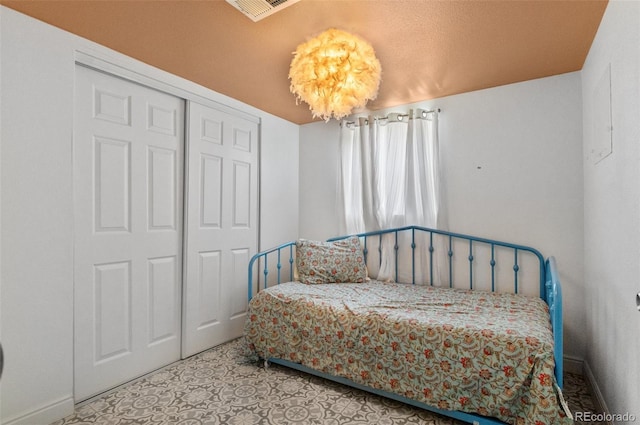 bedroom featuring tile patterned floors, baseboards, visible vents, and a closet