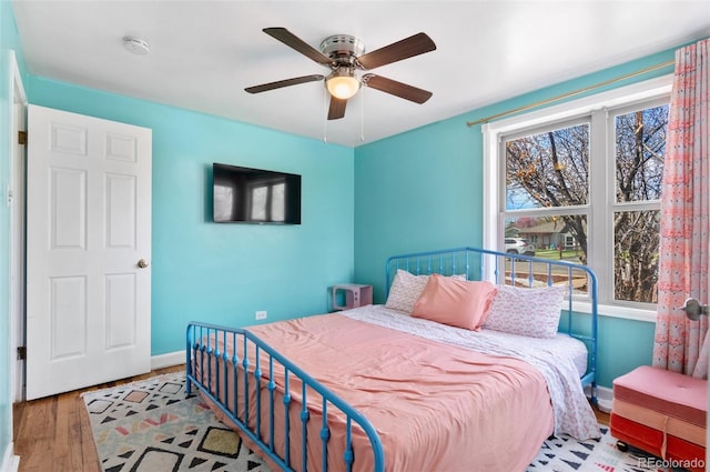 bedroom with ceiling fan, baseboards, and wood finished floors