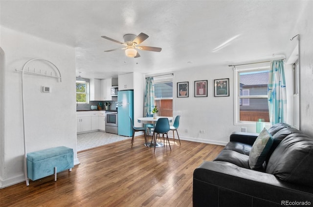living area with light wood finished floors, baseboards, and ceiling fan