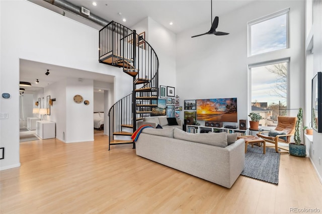 living room featuring a towering ceiling, light hardwood / wood-style flooring, and ceiling fan