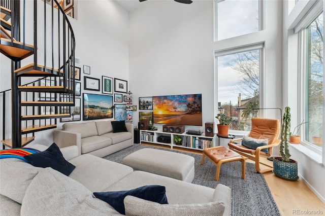 living room with hardwood / wood-style flooring, ceiling fan, and a high ceiling