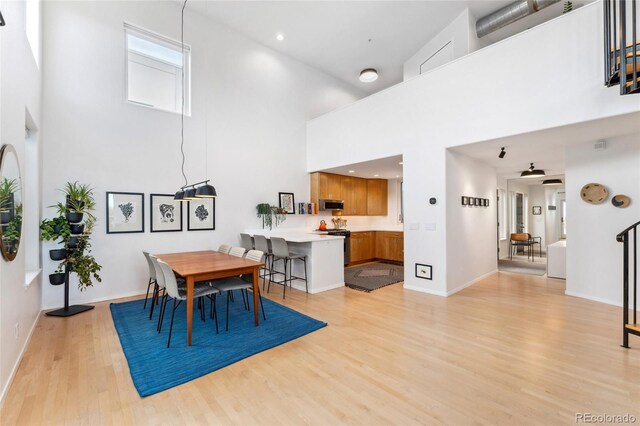 dining area with light hardwood / wood-style flooring and a high ceiling