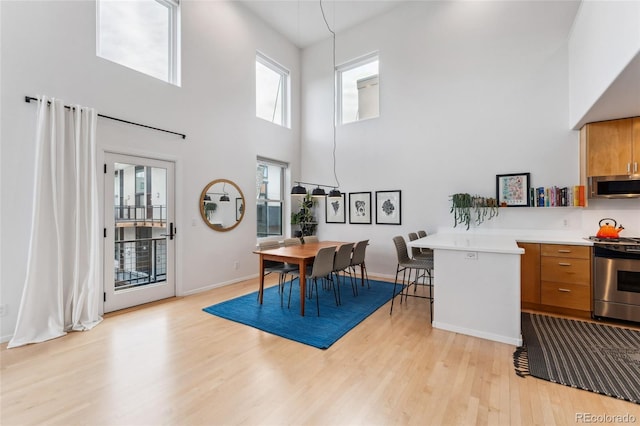 dining room featuring a towering ceiling and light wood-type flooring