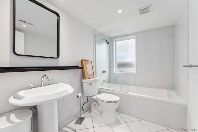 bathroom featuring tiled shower / bath, tile patterned floors, and toilet