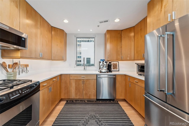 kitchen featuring appliances with stainless steel finishes, sink, and light wood-type flooring