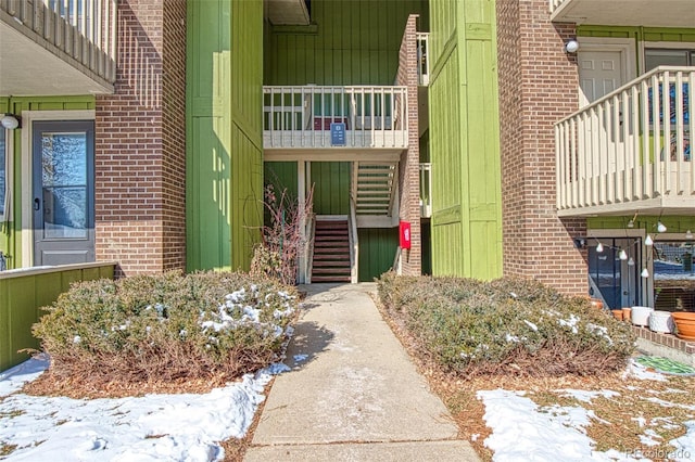 snow covered property entrance with brick siding