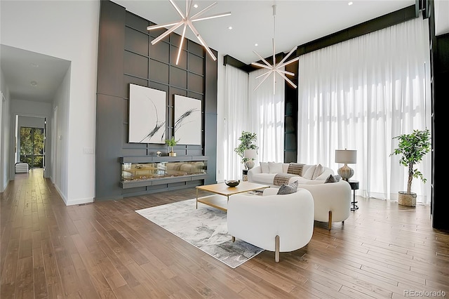 living room featuring a notable chandelier, hardwood / wood-style floors, and a high ceiling