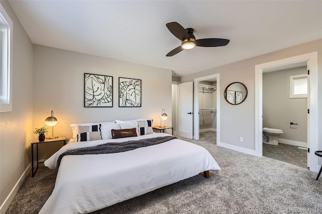 carpeted bedroom with ensuite bath, a closet, a walk in closet, and ceiling fan