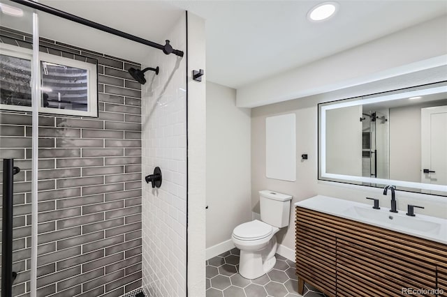 bathroom with toilet, tile patterned flooring, a tile shower, and vanity