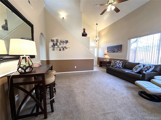 living room with ceiling fan, carpet, arched walkways, visible vents, and a high ceiling