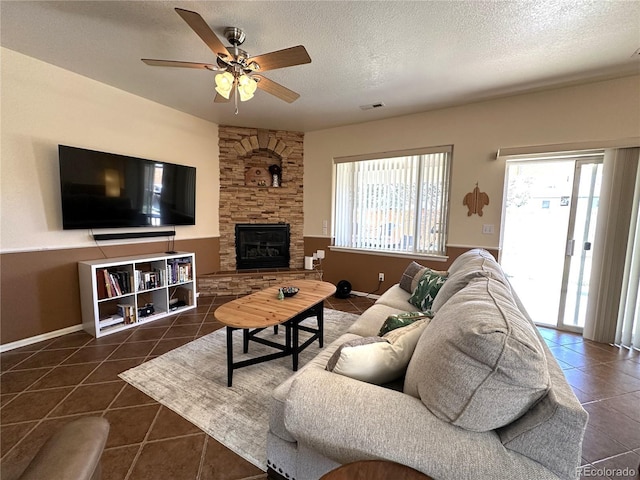 living room featuring dark tile patterned flooring, a healthy amount of sunlight, visible vents, and a textured ceiling
