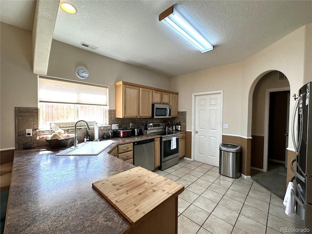 kitchen featuring visible vents, arched walkways, a sink, a textured ceiling, and stainless steel appliances
