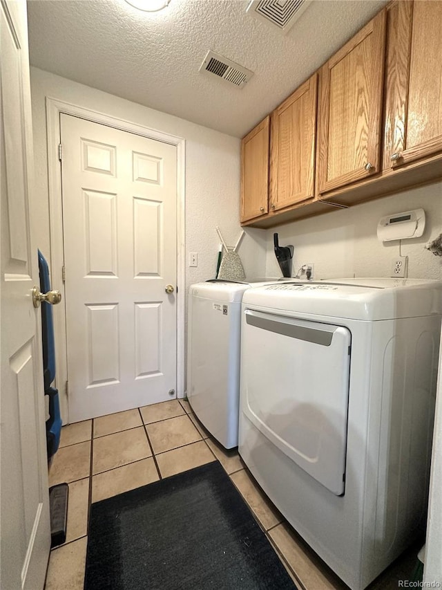 laundry room with light tile patterned floors, visible vents, independent washer and dryer, and cabinet space