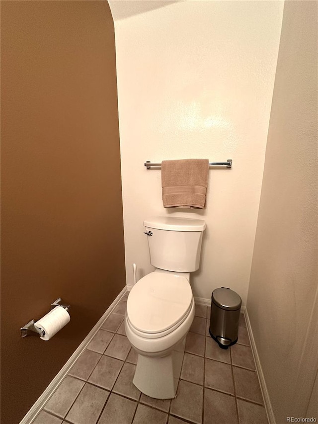 bathroom featuring tile patterned flooring, baseboards, and toilet