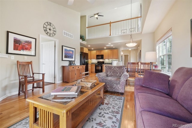 6701 W Yale Ave, Lakewood, CO 80227 - living room featuring light wood finished floors, ceiling fan, a high ceiling, and baseboards