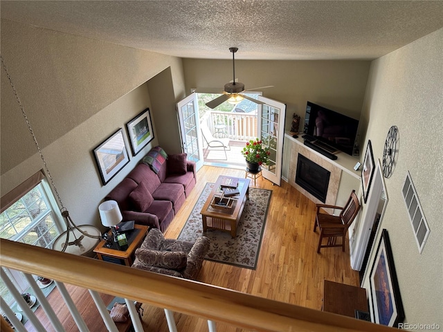6701 W Yale Ave, Lakewood, CO 80227 - living room featuring a textured wall, vaulted ceiling, plenty of natural light, wood finished floors, and a fireplace