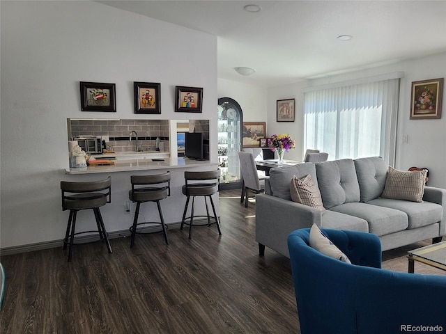 living room featuring dark wood-style floors and arched walkways