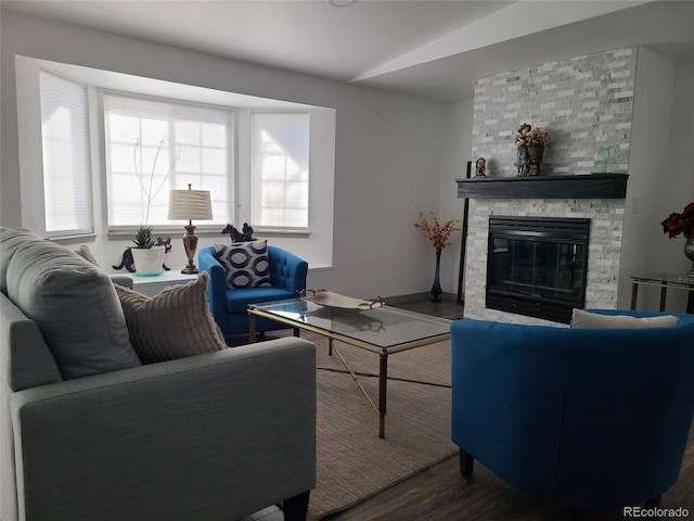 living room with a stone fireplace and wood finished floors