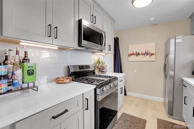 kitchen with appliances with stainless steel finishes, decorative backsplash, and light wood-type flooring