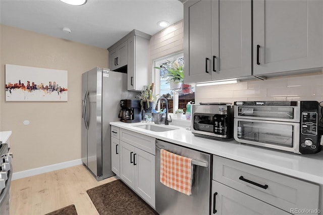 kitchen with gray cabinetry, sink, decorative backsplash, and appliances with stainless steel finishes