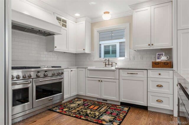 10 Oakmont Ln, Littleton, CO 80127 - kitchen with range with two ovens, custom range hood, white cabinetry, decorative backsplash, and recessed lighting