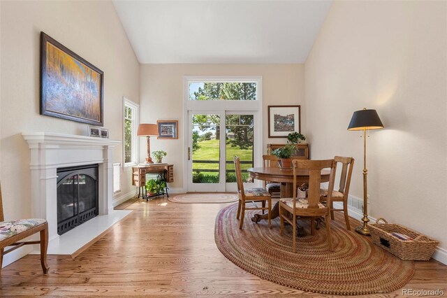 10 Oakmont Ln, Littleton, CO 80127 - dining area with a glass covered fireplace, light wood-type flooring, and high vaulted ceiling