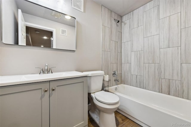 full bathroom featuring hardwood / wood-style flooring, tiled shower / bath, vanity, and toilet