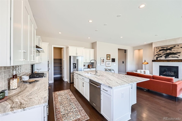 kitchen with sink, white cabinetry, light stone counters, stainless steel appliances, and a kitchen island with sink