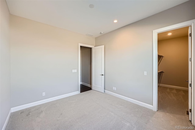 unfurnished bedroom with a spacious closet and light carpet