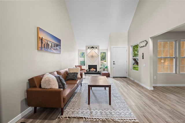 13025 E Bethany Pl, Aurora, CO 80014 - living room featuring high vaulted ceiling, light wood-type flooring, plenty of natural light, and a lit fireplace
