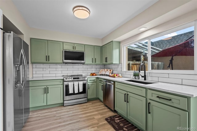13025 E Bethany Pl, Aurora, CO 80014 - kitchen featuring green cabinetry, appliances with stainless steel finishes, backsplash, and light wood-style floors