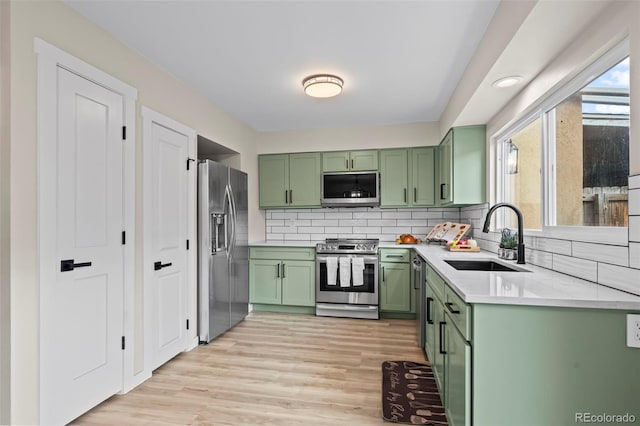 13025 E Bethany Pl, Aurora, CO 80014 - kitchen with green cabinets, stainless steel appliances, light countertops, light wood finished floors, and tasteful backsplash