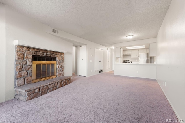 unfurnished living room with carpet flooring, a textured ceiling, and a fireplace