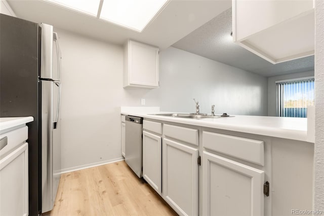 kitchen featuring light wood-type flooring, stainless steel appliances, white cabinetry, and sink