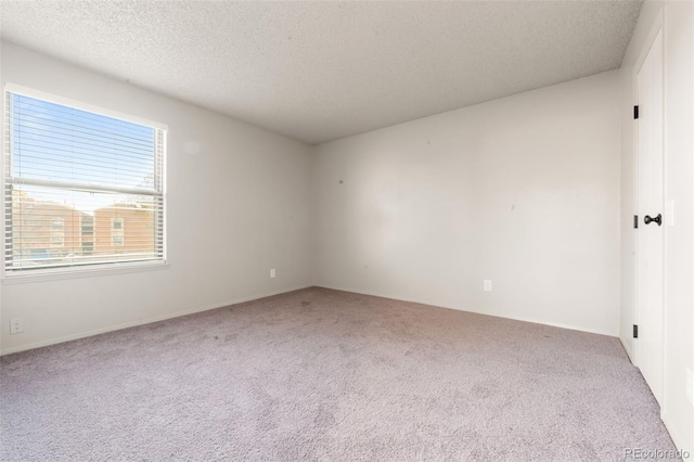 unfurnished room with light colored carpet and a textured ceiling