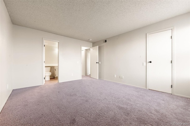 unfurnished bedroom featuring carpet, a textured ceiling, and ensuite bath