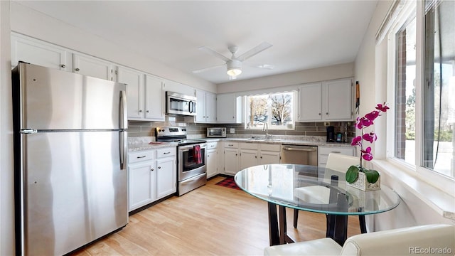 kitchen featuring decorative backsplash, light wood-type flooring, stainless steel appliances, and white cabinetry