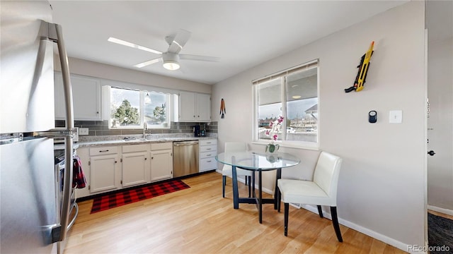 kitchen featuring backsplash, white cabinets, stainless steel appliances, and light hardwood / wood-style floors